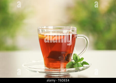 Tea bag dipped in cup with hot beverage on table Stock Photo