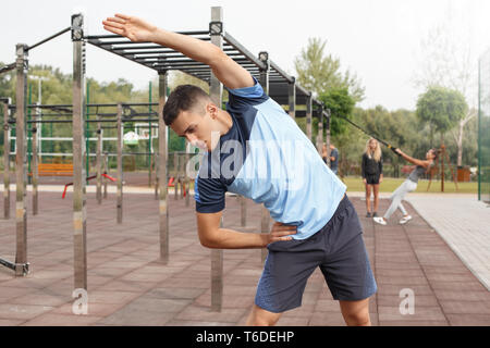 Young sportsman maintaining healthy lifestyle doing warm up outdoors leaning to the right concentrated Stock Photo