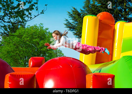 Happy little girl having lots of fun while jumping from ball to ball on an inflate castle. Stock Photo