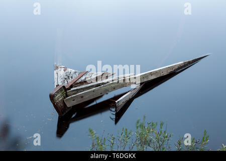 Sunken rowboat abandoned in small forest lake Stock Photo