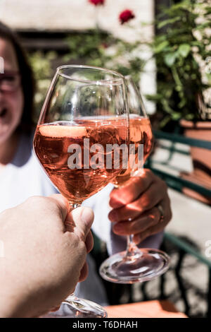 Woman and another person sitting at a table toasting with wine glasses of Aperol Spritz. Stock Photo