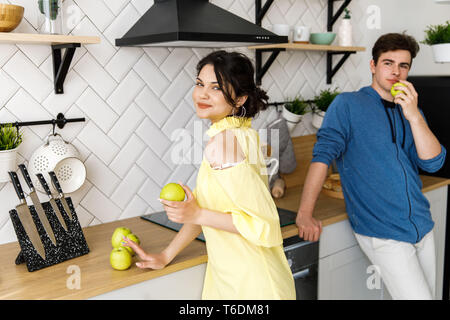 Young cute smiling couple cooking together at kitchen at home. A couple - a girl and a boy who spend time together for cooking. Stock Photo