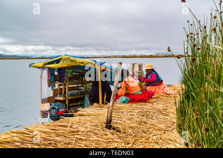 PUNO, PERU - FEBRUARY 1, 2016 : Uru woman wearing traditional cloths buying food and necessary things from a boat market at Uros Floating Island on La Stock Photo