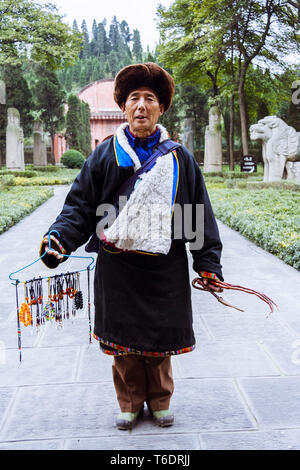 Chengdu, Sichuan province, China :  A trinkets seller poses in front of the Yongling Mausoleum or Tomb of Wang Jian (847–918), a former general and em Stock Photo