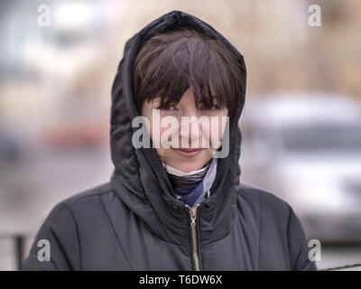 Portrait of a young woman in a hood on a city street Stock Photo