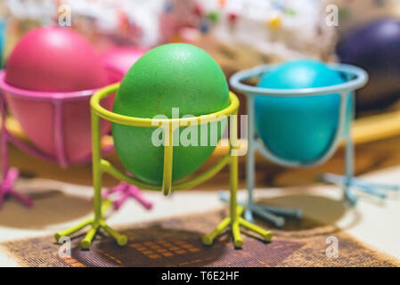 Three Easter painted eggs in holders on table Stock Photo
