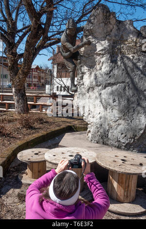 Woman photographing a Bronze statue that commemorates the ski guides of the Fassa valley a trhe village of Campitello Stock Photo