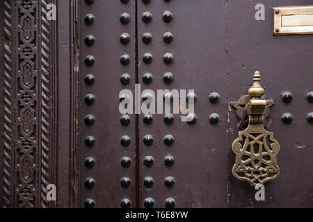 Typical wooden Moroccan door detail with metal decoration and reinforcements and ornate door knocker Stock Photo