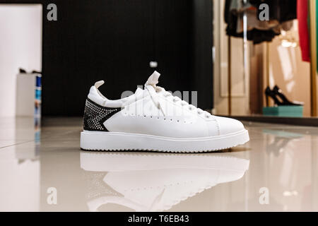 stylish white sneaker with a star ornament made of rhinestones on the backdrop on the light floor Stock Photo
