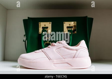fashionable pink sneakers with thick soles and a green bag in the background on the white shelf of the store Stock Photo