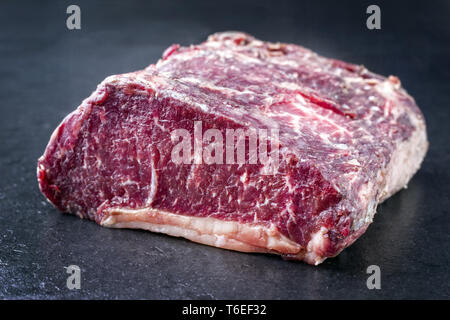 Raw dry aged Kobe Roastbeef wrapped in fat as close-up on a slate Stock Photo