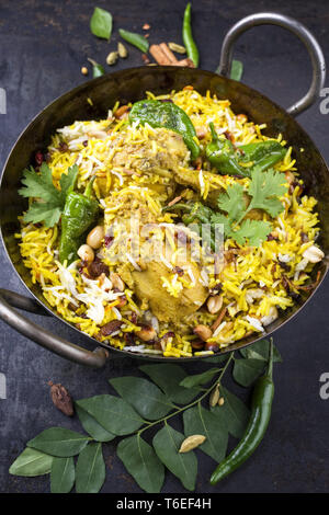 Indian chicken biryani with nuts and raisins as close-up in a korai ...