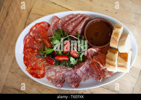 A platter of mixed cured meats and salad served with sliced french bread Stock Photo