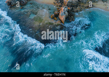 Looking down at waves crushing over rocks - aerial view Stock Photo