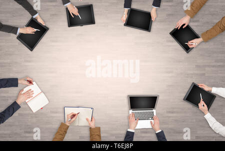 Group of people with devices in hands having desk discussion and making reports together on laptop, tablet, notebook  Stock Photo