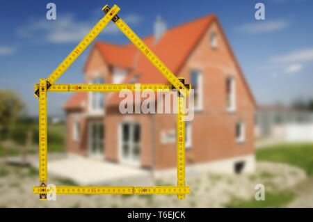 shell of house under construction with folding ruler in hand of real estate agent Stock Photo