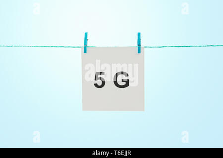 Word 5G on white note paper hanging on rope against sunny blue sky Stock Photo