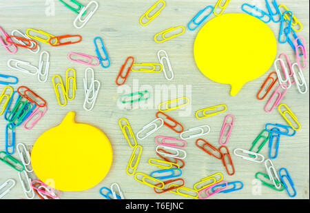 Yellow Speech bubble note with set of colorful paper clips on wooden background.business creativity concepts.Flat lay design Stock Photo