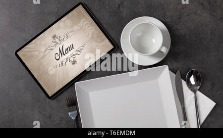 Tablet with stylish restaurant logo and laid table  Stock Photo