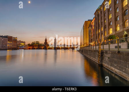 The banks of the river Spree in Berlin with the Oberbaum Bridge in the back after sunset Stock Photo