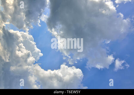 Blue sky background with fluffy cumulus white and gray clouds at sunlight backlit. Majestic heaven - meteorology or religious concept. Beauty and ener Stock Photo