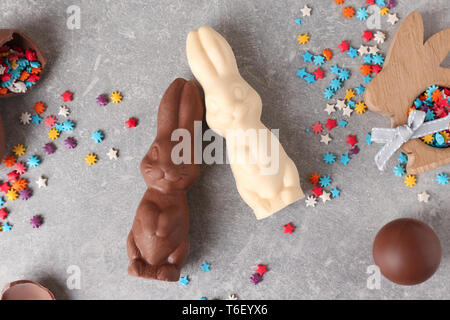 Beautiful Easter composition with chocolate bunnies, eggs and sprinkles on gray background Stock Photo