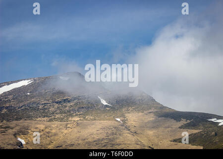 Fogs and mist rolling in on an impressive, pointy, rocky Kopren summit under a deep blue sky Stock Photo