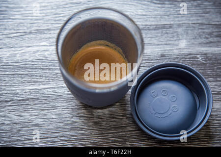 Top view of a reusable glass coffee cup sitting next to it's silicone lid. Using glass and silicon means there is no plastic taste when drinking. Stock Photo