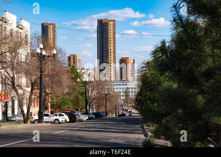 View of one of the streets of Khabarovsk in the daytime against a blue bright sky and white clouds. The combination of ancient architecture with moder Stock Photo