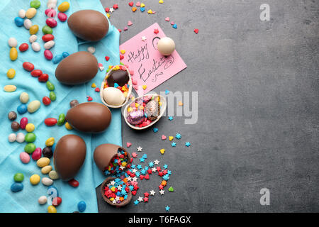 Composition with chocolate Easter eggs, colorful sprinkles and candies on gray background Stock Photo