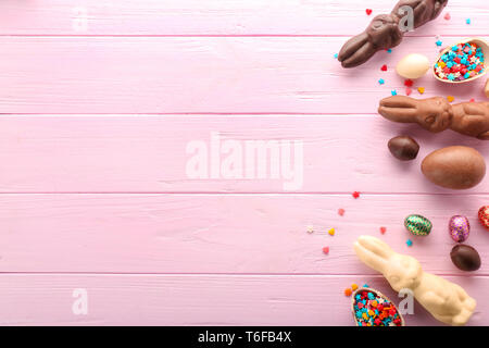 Easter composition with chocolate bunnies and eggs on color wooden background Stock Photo