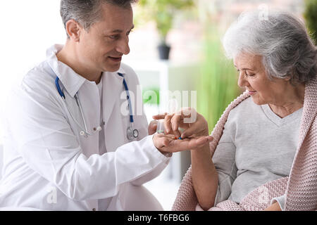Doctor giving pills to elderly woman, indoors Stock Photo