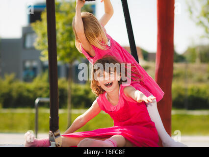 Two young girls playing happily on playground outdoor Stock Photo