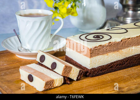 Three-layer cake and cup with hot tea Stock Photo