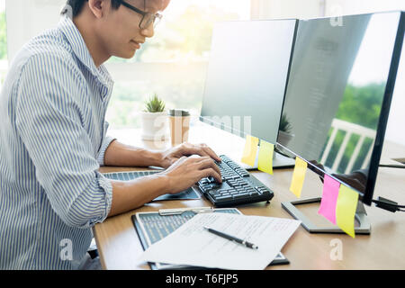 Serious busy hipster young web software developer programmer is coding or programming on a desktop computer information in modern office technologies  Stock Photo