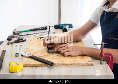 Carpenter working carefully looking at the plans work in carpentry. He is successful entrepreneur at his workplace. hammering a nail Supports On Build Stock Photo