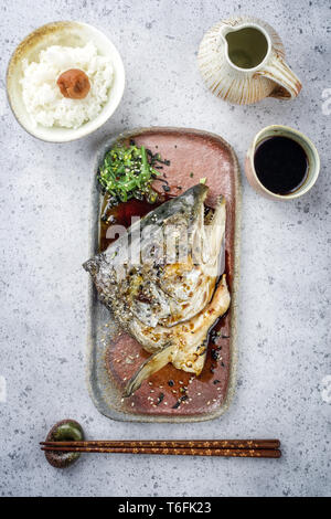 Traditional barbecue Japanese Kama Yaki broiled salmon fish head with rice and umeboshi as close-up on a plate Stock Photo