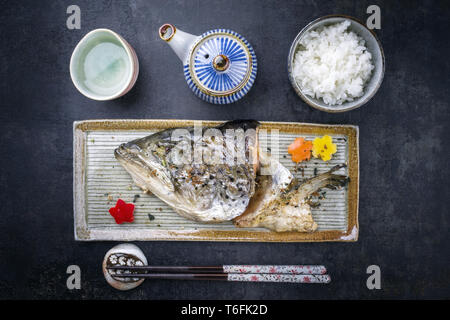 Traditional barbecue Japanese Kama Yaki salmon fish head with rice as to view on a plate Stock Photo