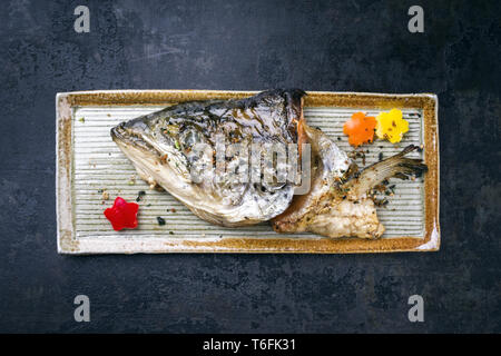 Traditional Japanese barbecue Kama Yaki salmon fish head as close-up on a plate Stock Photo