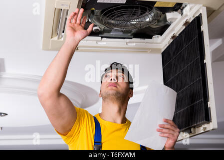 Repairman repairing ceiling air conditioning unit Stock Photo