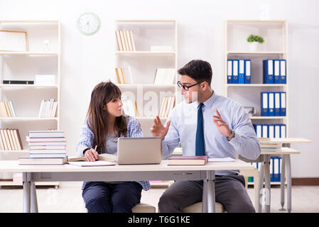 Male lecturer giving lecture to female student Stock Photo