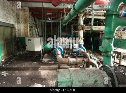 Abandoned water pump room interior showing pipework and valves Stock Photo