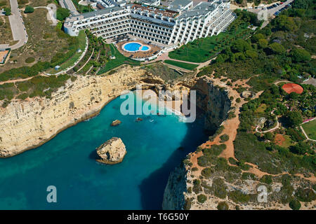 AERIAL VIEW. Luxury resort overlooking Vale Covo Beach and the stunning, colorful cliffs. Carvoeiro, Lagoa, Algarve, Portugal. Stock Photo