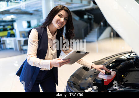 Beautiful sale-manger inspect new car with help of tablet in dealership center Stock Photo