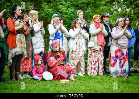 People put their hands together during the Beltane celebrations at Glastonbury Chalice Well, where people gather to observe a modern interpretation of the ancient Celtic pagan fertility rite of Spring. Stock Photo