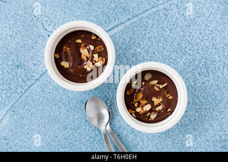 Top view of homemade chocolate dessert in white ramekins on blue concrete background. Stock Photo