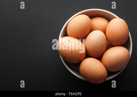 brown eggs in bowl isolated on dark background. top view Stock Photo