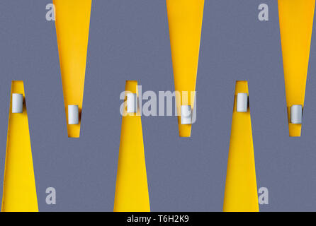 Abstract geometric architecture feature with zigzag yellow and dark purple color wall and hanging wall lights, minimalist colorful background Stock Photo