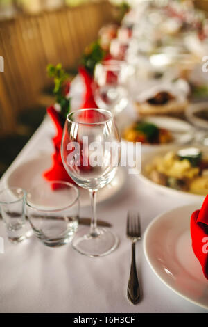 Restaurant interior, serving, wine and water glasses, plates, forks and knives on textile napkins stand in row on vintage gray wooden table. Concept b Stock Photo