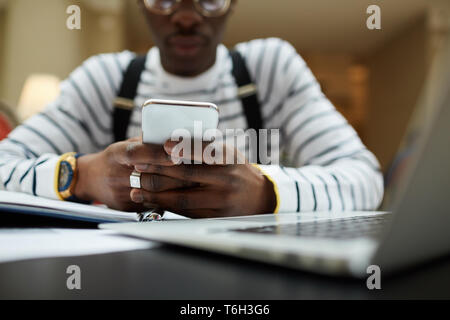 Closeup  of contemporary African student using smartphone while studying in library, copy space Stock Photo
